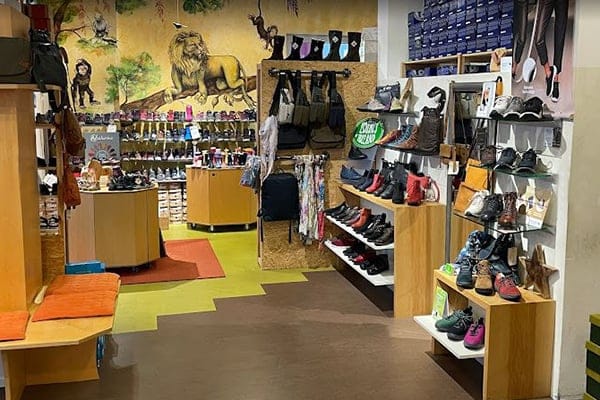Innenansicht eines Schuhgeschäfts mit bunten Schuhen auf Regalen und einem Wandbild eines Löwen