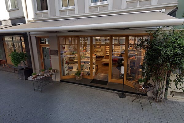 Einladender Eingang eines gemütlichen Schuhgeschäfts in einer Einkaufsstraße Außenansicht eines charmanten Schuhladens mit großen Glasscheiben und einladender Dekoration in einer belebten Straße