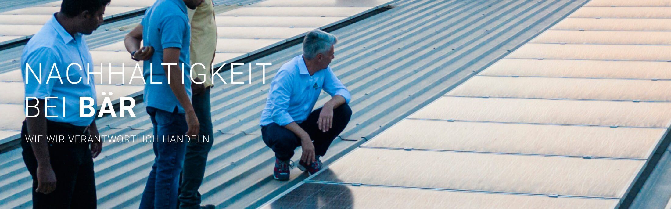 Personen auf einem Dach mit Solarmodulen, Darstellung der Nachhaltigkeit bei Bär