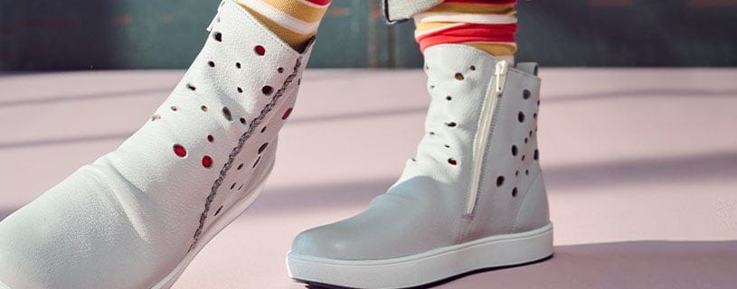 Stylische weiße Stiefeletten mit Lochmuster für einen trendigen Look Weiße Stiefeletten mit Lochmuster und Reißverschluss auf rosa Boden