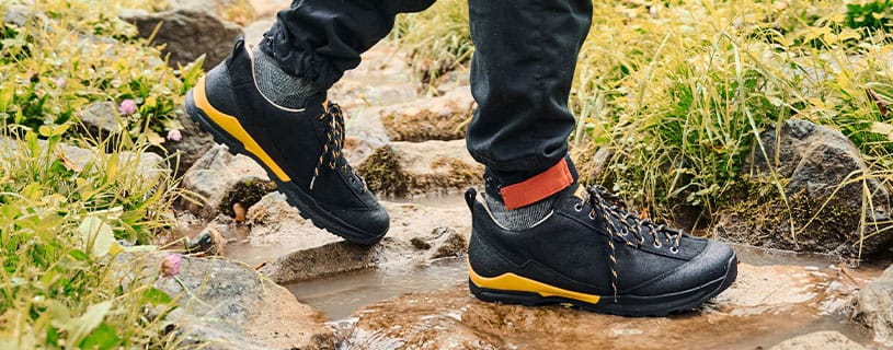 Wasserdichte Wanderschuhe auf steinigem Pfad Person trägt wasserdichte Wanderschuhe und überquert einen steinigen Pfad im Freien