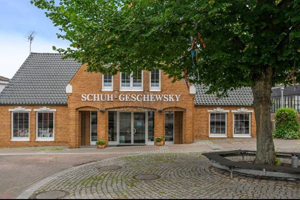 Backsteingebäude des Schuh-Geschäfts Geschewsky mit Baum im Vordergrund