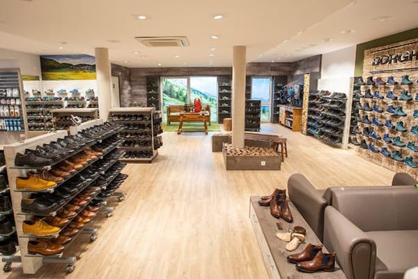 Innenansicht eines modernen Schuhgeschäfts mit vielen Regalen voller Schuhe und einer gemütlichen Sitzecke.