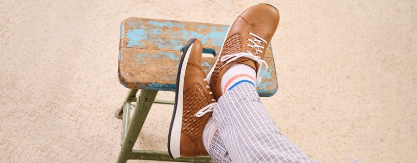 Braune Freizeitschuhe auf einem blauen Hocker Person trägt braune Freizeitschuhe und gestreifte Hose, Füße auf einem alten blauen Hocker