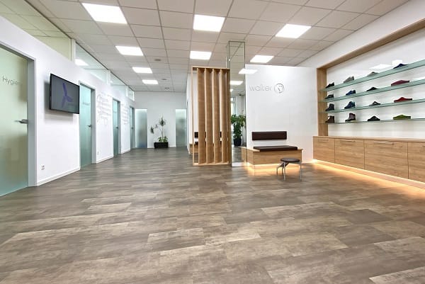 Moderner Showroom mit Holzfußboden und Schuhpräsentation Innenansicht eines modernen Showrooms mit Holzfußboden, einer Sitzgelegenheit und einer beleuchteten Schuhpräsentation an der Wand.