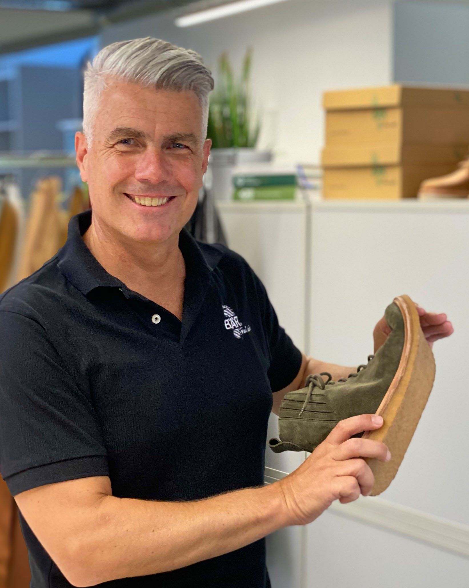 Man holding a green shoe in a retail store Smiling man showing a green shoe with a cork sole in a shop environment