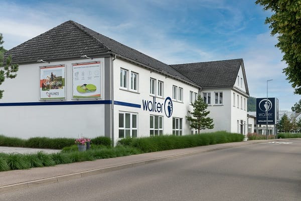 Außenansicht des Walter-Gebäudes bei blauem Himmel Das Bild zeigt die Außenansicht eines weißen Gebäudes mit dem Logo von Walter, einem Fachgeschäft, bei strahlend blauem Himmel.