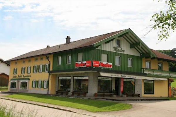 Außenansicht eines traditionellen bayerischen Ladengeschäfts mit grünem Holzgiebel und großer Fensterfront