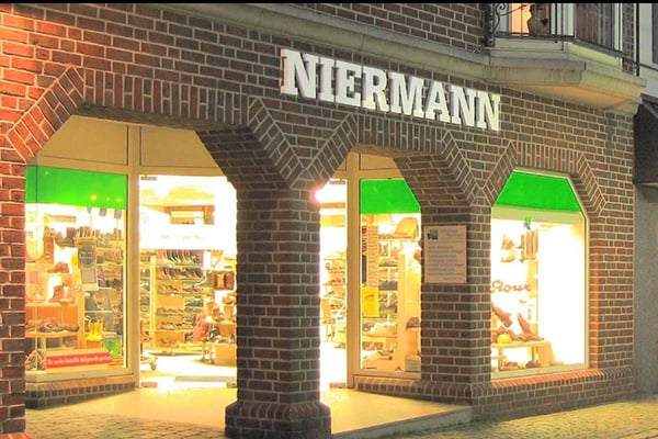 Außenansicht des Niermann-Schuhgeschäfts mit Backsteinfassade und beleuchtetem Schaufenster
