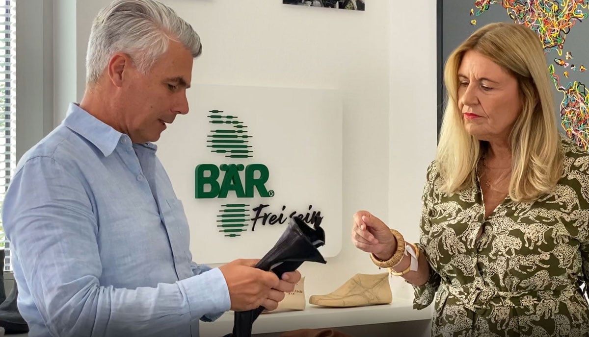 Personen diskutieren Produktdetails in einem BÄR-Schuhe-Geschäft Eine Frau und ein Mann besprechen ein Schuhprodukt im BÄR-Schuhe-Geschäft