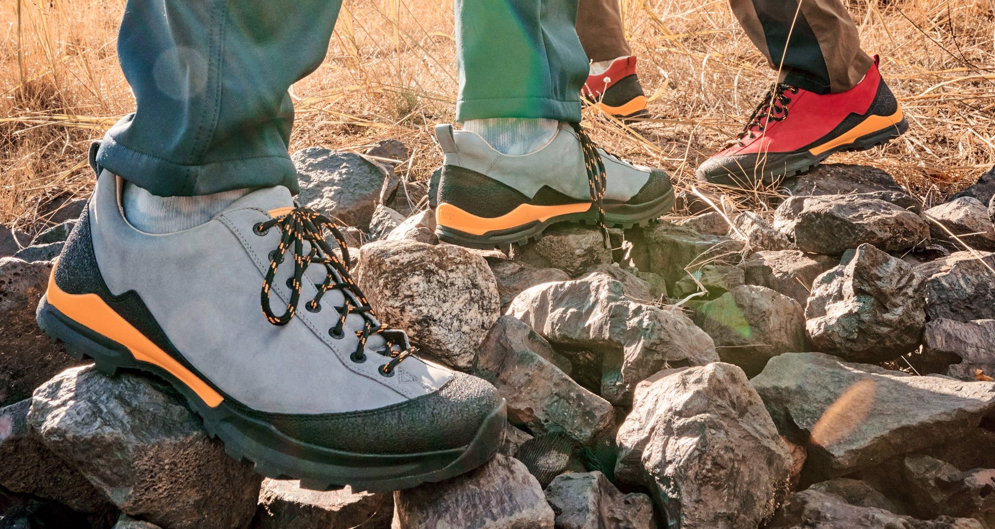 Robuste Wanderschuhe für jedes Terrain Nahaufnahme von zwei Personen, die robuste Wanderschuhe auf felsigem Untergrund tragen, ideal für Outdoor-Aktivitäten