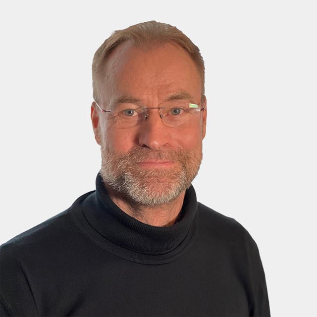 Porträt eines lächelnden Mannes mit Brille und Bart Ein lächelnder Mann mittleren Alters mit Brille und Bart, trägt einen schwarzen Rollkragenpullover vor einem neutralen Hintergrund