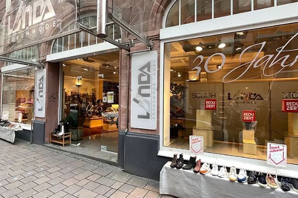 Außenansicht eines Schuhgeschäfts mit Schaufensterdekoration zum 30-jährigen Jubiläum und Schildern für reduzierte Preise