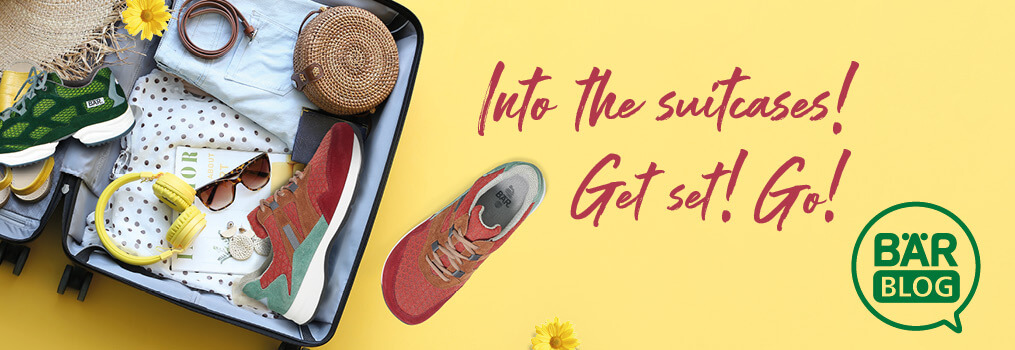 Travel Essentials Packed in Suitcase with Shoes and Accessories Open suitcase with sneakers, sunglasses, headphones, and summer accessories on a yellow background with the text 'Into the suitcases! Get set! Go!'