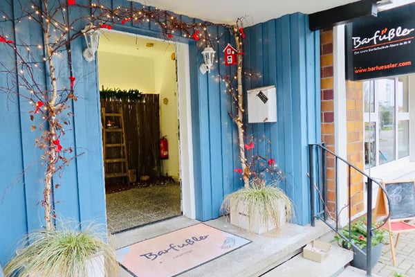 Blick auf den blau gestrichenen Eingangsbereich eines Geschäfts, dekoriert mit Lichtern und Pflanzen