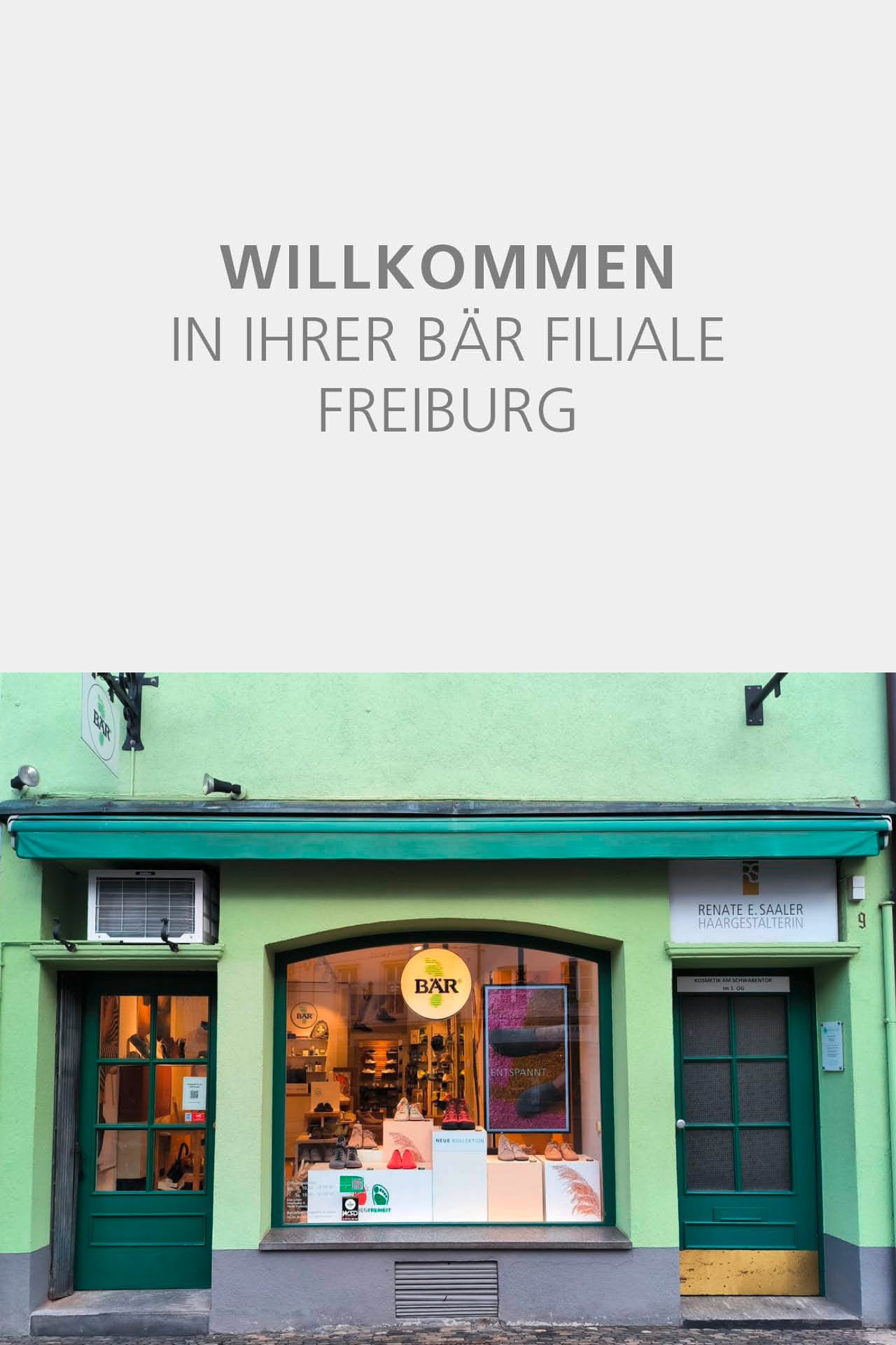 Die Außenansicht der BÄR Filiale in Freiburg mit grünem Eingangsbereich und Schaufenstern, die Schuhe ausstellen.