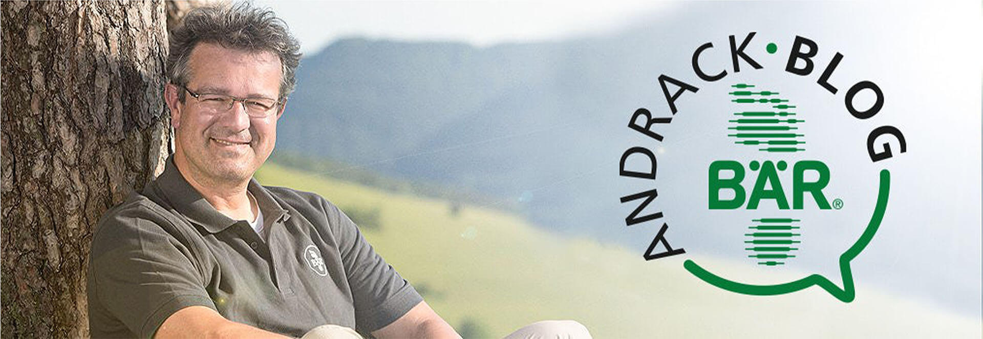 Man sitting against a tree with Andrack Blog and BÄR logo A man smiling while leaning against a tree, next to the Andrack Blog and BÄR logo