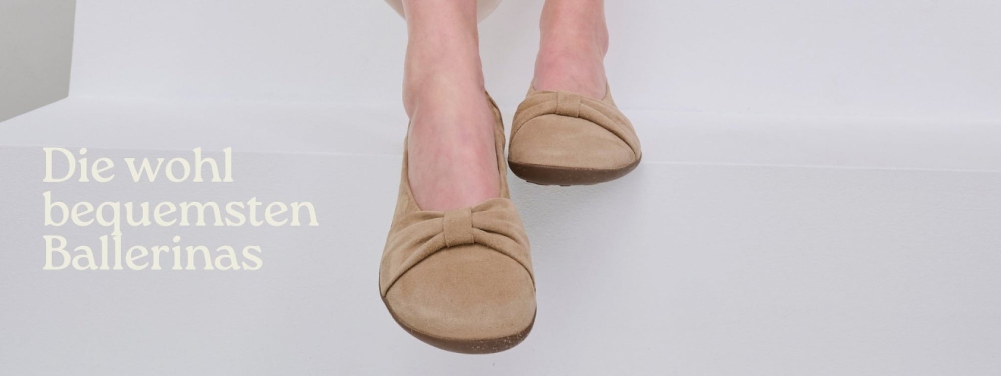 Nahaufnahme von beigen Ballerinas an den Füßen einer Person auf weißem Hintergrund