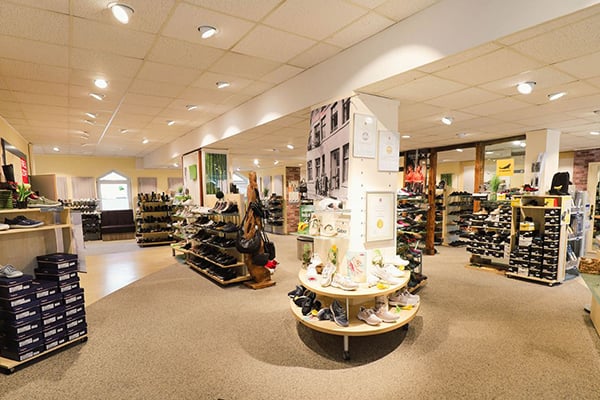 Innenansicht eines Schuhgeschäfts mit Regalen voller Schuhe und moderner Beleuchtung