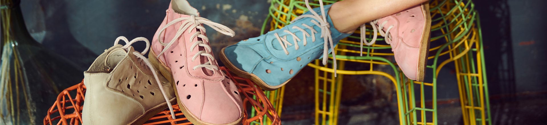 Pastellfarbene Kinderschuhe aus Leder mit Lochmuster Bequeme Kinderschuhe in Pastellfarben mit Schnürsenkeln und Lochmuster auf bunten Stühlen