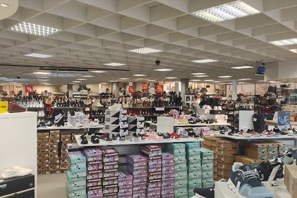 Innenansicht eines Schuhgeschäfts mit vielen Schuhen und Verkaufsangeboten auf Regalen und Tischen