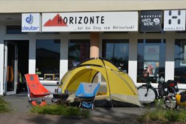 Zelt, Campingstühle und Fahrräder vor dem Horizont Outdoor-Geschäft ausgestellt