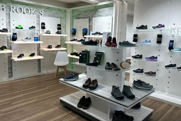 Innenansicht eines modernen Schuhladens mit einer großen Auswahl an Sportschuhen auf weißen Regalen