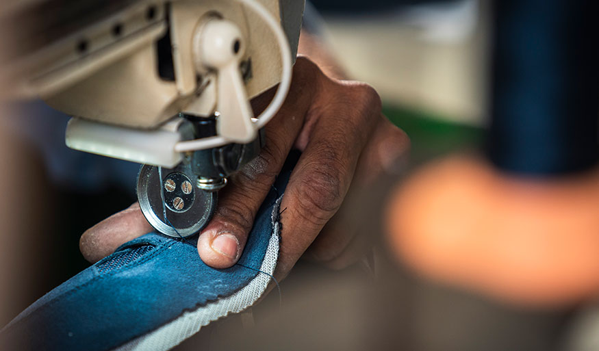 Präzises Nähen mit einer Nähmaschine Eine Person näht einen Stoff mit einer Nähmaschine, Nahaufnahme der Hand und des Stoffes.
