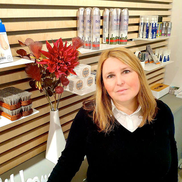 Frau vor einem Regal mit Pflegeprodukten und Blumenarrangement Frau steht vor einem Regal, das mit Pflegeprodukten und einem Blumenarrangement dekoriert ist.