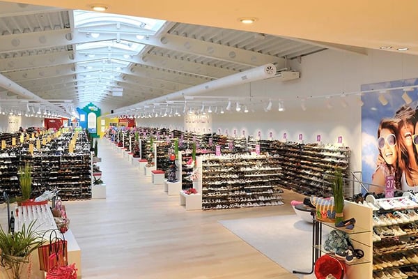 Blick in eine weitläufige, helle Schuhabteilung mit Regalen voller Schuhe in einem modernen Einkaufszentrum