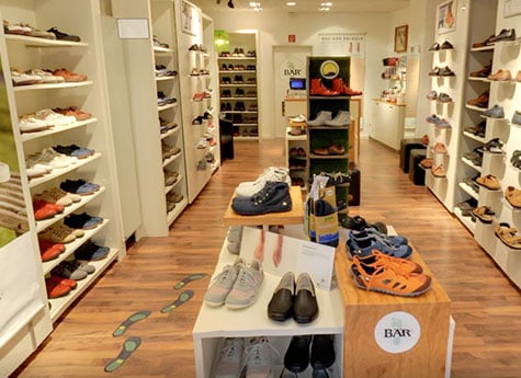 Interior view of a stylish shoe store with various footwear on display A well-organized shoe store showcasing sneakers, sandals, and formal shoes on wooden shelves