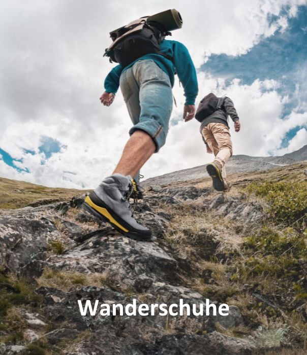 Zwei Wanderer steigen einen felsigen Bergpfad hinauf, tragen Rucksäcke und robuste Wanderschuhe.