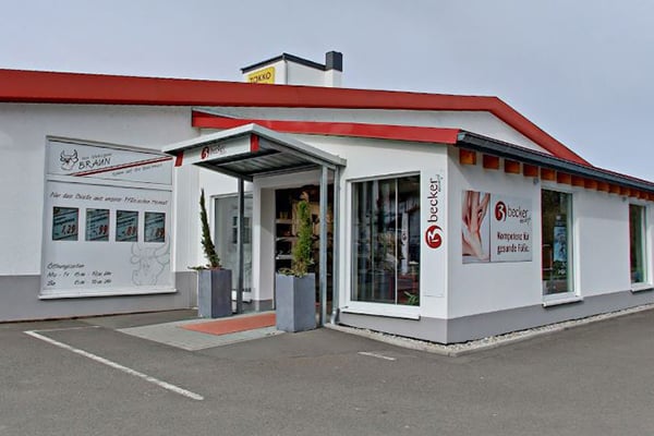 Außenansicht eines modernen Geschäftsgebäudes für Matratzen mit markanter roter Dachkante und großem Markenlogo.