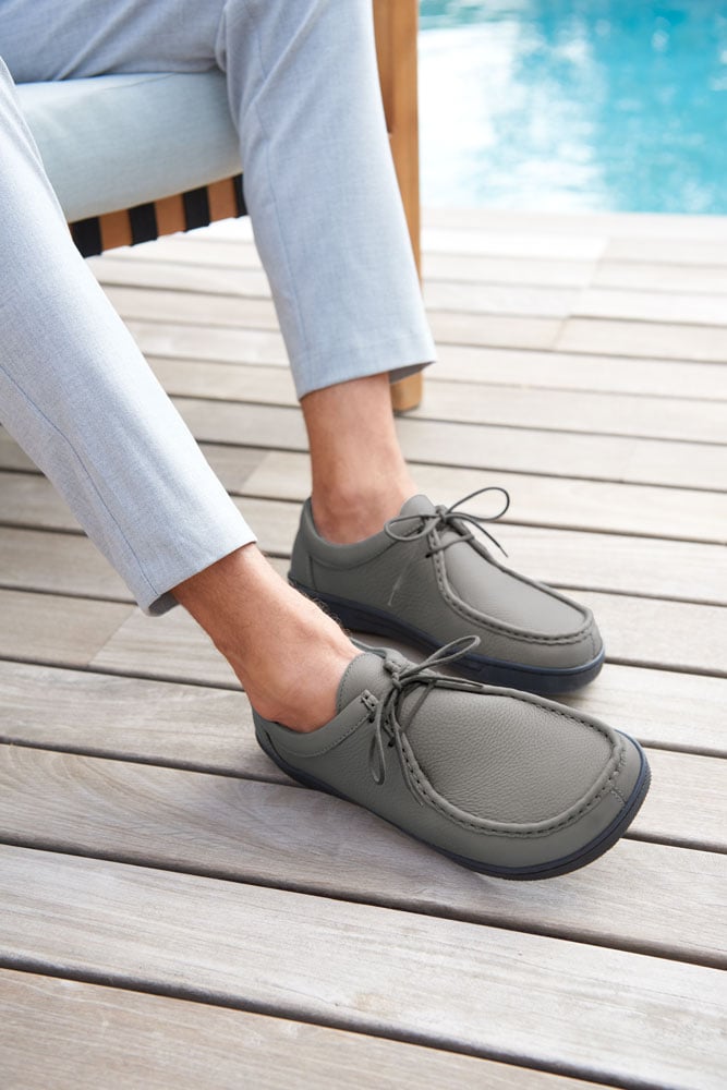 Mann tr&auml;gt graue Freizeitschuhe neben einem Pool auf Holzboden