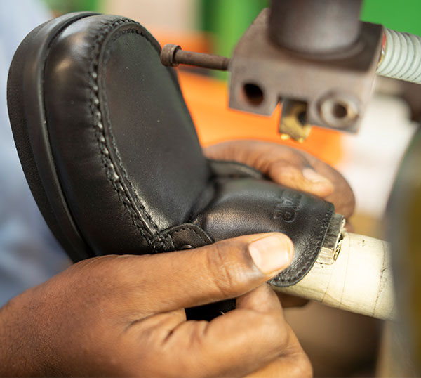 Nahaufnahme eines handgefertigten Lederschuhs in der Produktionsphase mit N&auml;hen von Details in einer Werkstatt