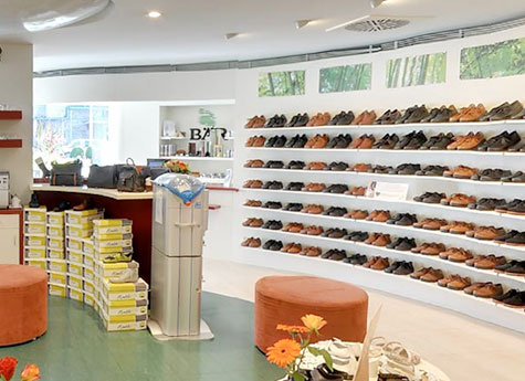 Schuhgeschäft mit großer Auswahl an Herrenschuhen Innenansicht eines Schuhgeschäfts mit Regalen voller Herrenschuhe und einer gemütlichen Sitzecke