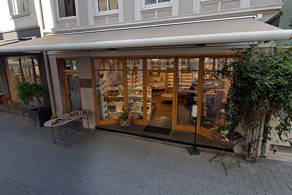 Einladender Eingang eines gemütlichen Schuhgeschäfts in einer Einkaufsstraße Außenansicht eines charmanten Schuhladens mit großen Glasscheiben und einladender Dekoration in einer belebten Straße