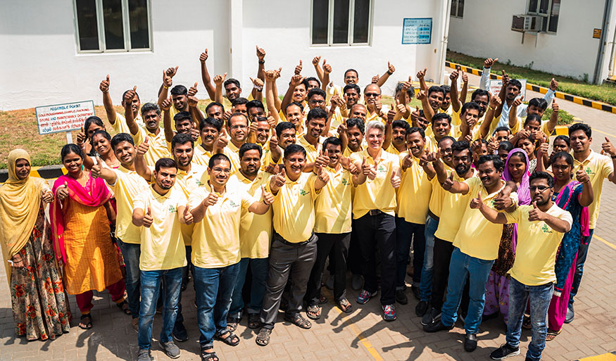 Group of people wearing yellow shirts giving thumbs up outdoors Large group of people in yellow shirts with thumbs up, gathered outside a building