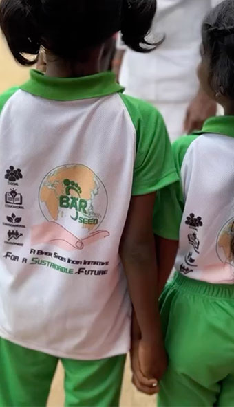 Kinder in grünen und weißen Schuluniformen mit nachhaltigem Slogan Zwei Kinder in grünen und weißen Schuluniformen mit einem Logo und dem Text 'For a Sustainable Future' auf dem Rücken.
