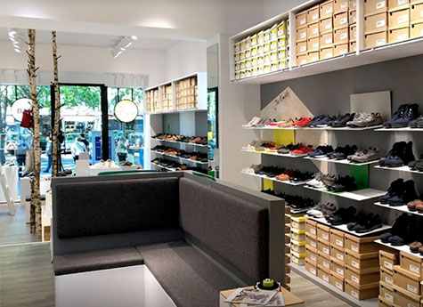 Moderne Schuhboutique mit vielfältiger Schuhkollektion und gemütlicher Sitzecke Innenansicht einer modernen Schuhboutique mit Regalen voller verschiedenfarbiger Schuhe und einer Sitzecke