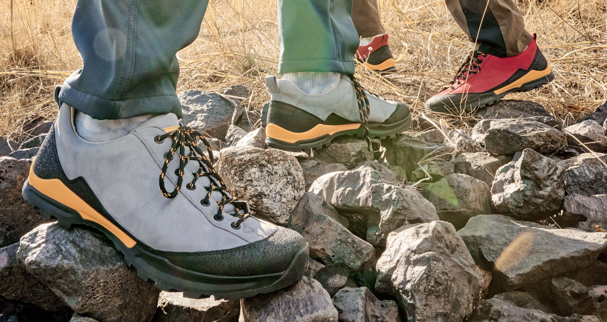 Robuste Wanderschuhe für jedes Terrain Nahaufnahme von zwei Personen, die robuste Wanderschuhe auf felsigem Untergrund tragen, ideal für Outdoor-Aktivitäten