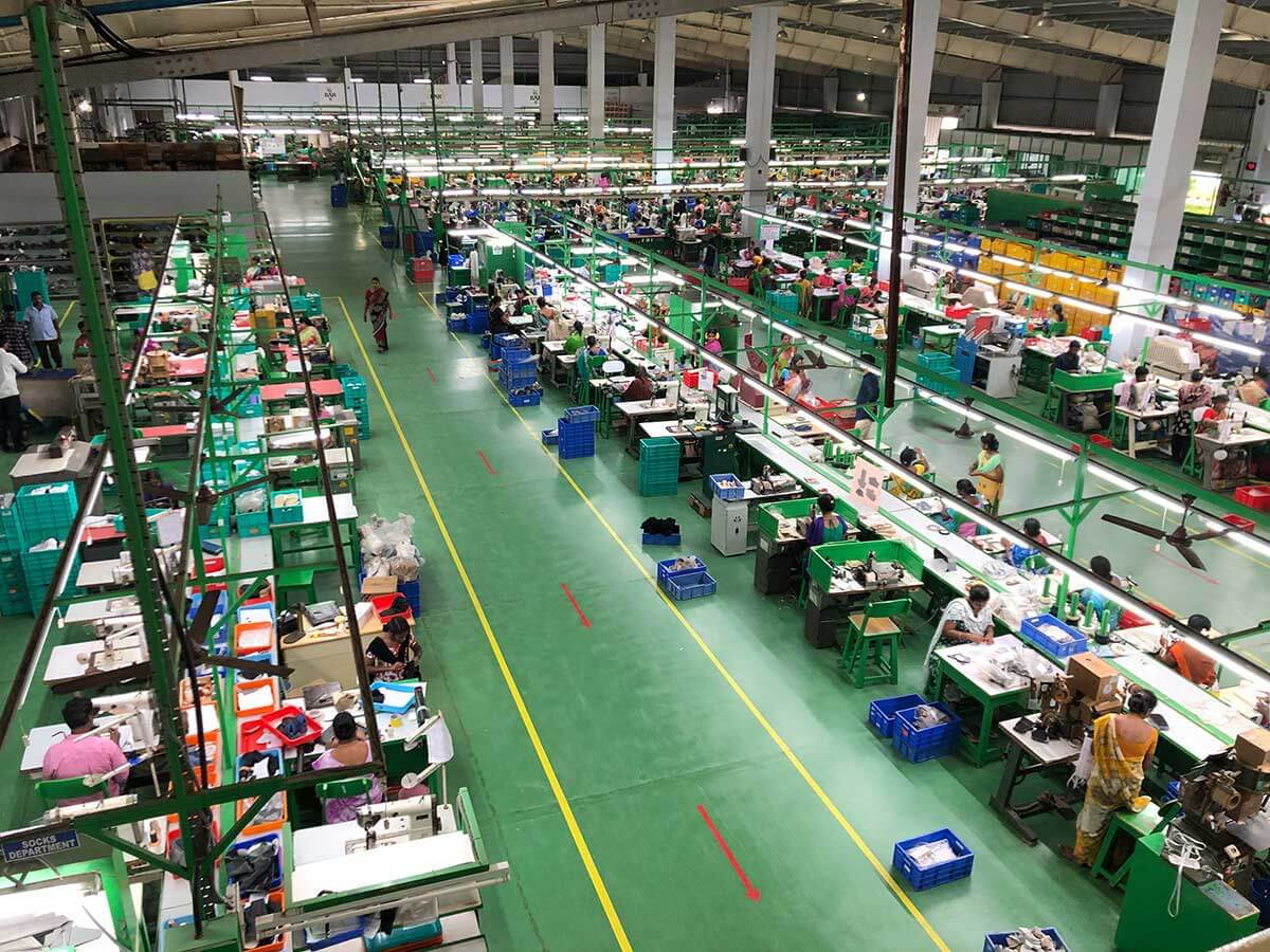 Modern textile factory with workers at sewing machines Aerial view of a textile factory showing rows of workers at sewing stations in a large, well-lit industrial space