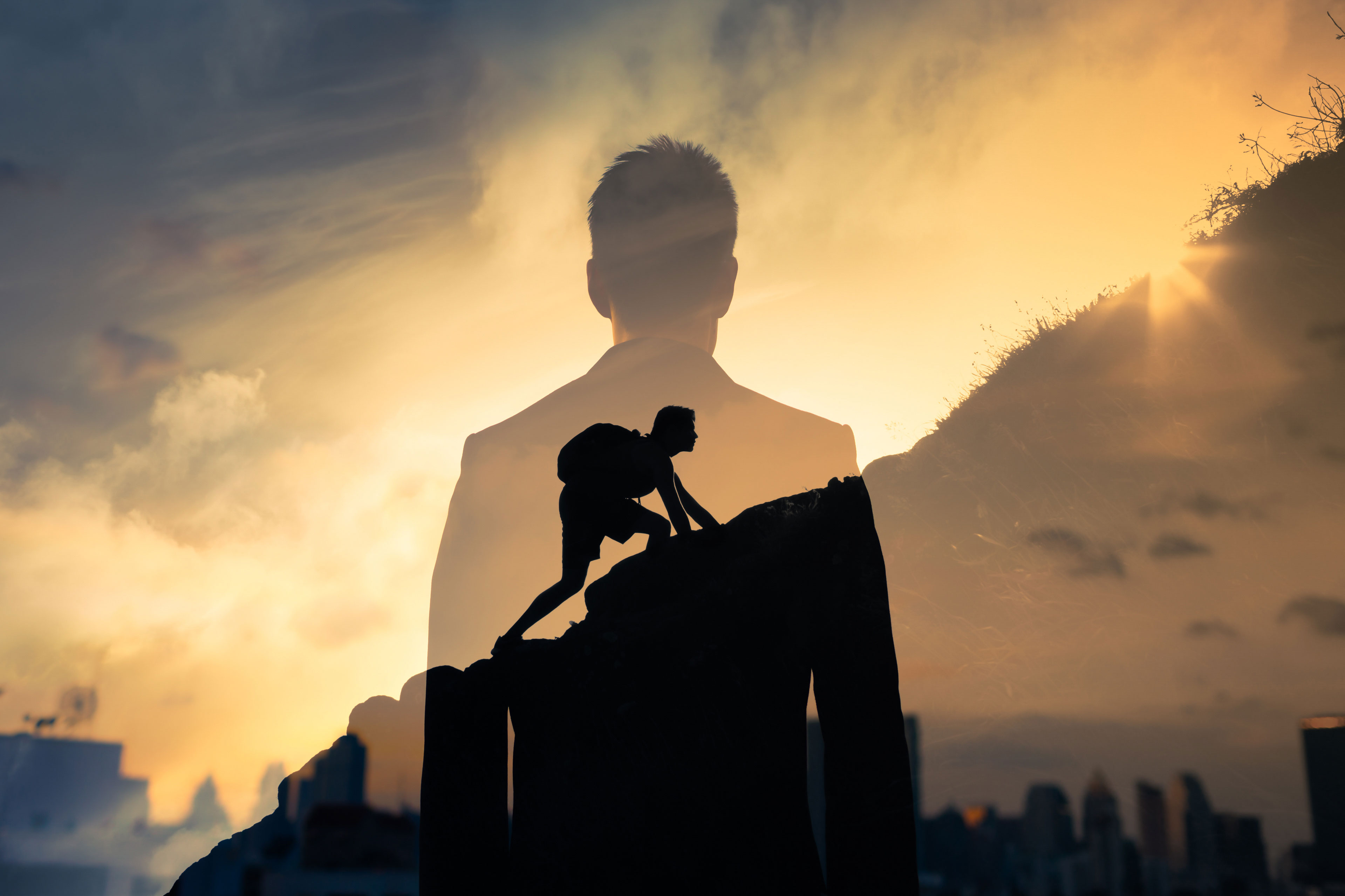 Silhouette of person climbing mountain with sunrise background A double exposure image of a person climbing a mountain overlaid with a man's silhouette and a sunrise.