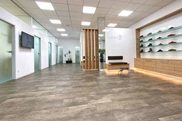 Moderner Showroom mit Holzfußboden und Schuhpräsentation Innenansicht eines modernen Showrooms mit Holzfußboden, einer Sitzgelegenheit und einer beleuchteten Schuhpräsentation an der Wand.