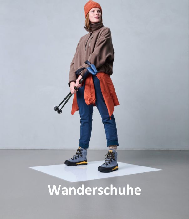 Frau in Outdoor-Kleidung und Wanderschuhen mit Wanderstöcken in einer minimalistischen Umgebung