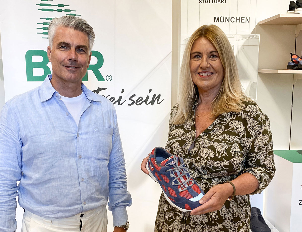 Business meeting showcasing a new sneaker model Two people at a business event presenting a red and blue sneaker
