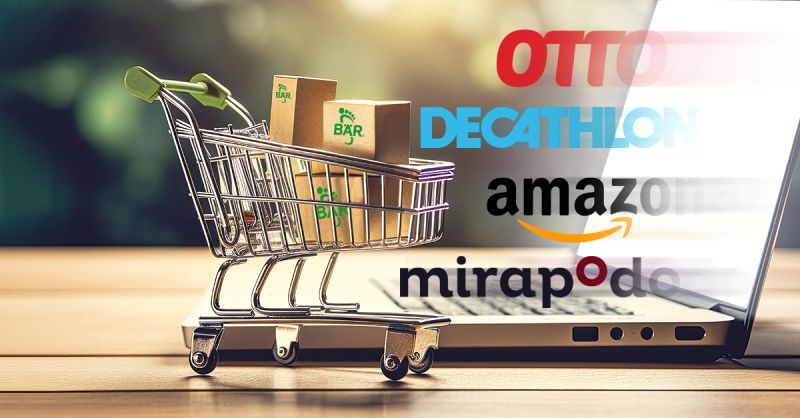 Einkaufswagen mit Paketen vor Laptop und Online-Shop-Logos Ein kleiner Einkaufswagen mit Paketen steht vor einem Laptop. Im Hintergrund sind Logos populärer Online-Shops wie Otto, Decathlon, Amazon und Mirapodo zu sehen.