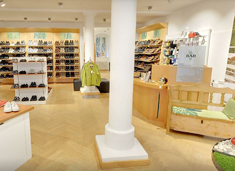 Moderne Schuhboutique mit abwechslungsreichem Schuhangebot Innenansicht einer Schuhboutique mit verschiedenen Schuhregalen und einer gemütlichen Sitzecke.