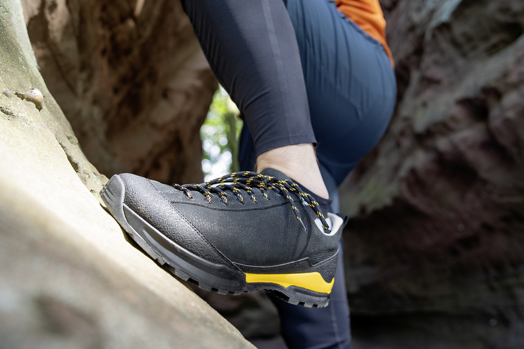 Close-up of black hiking shoes with yellow accents on a rocky terrain