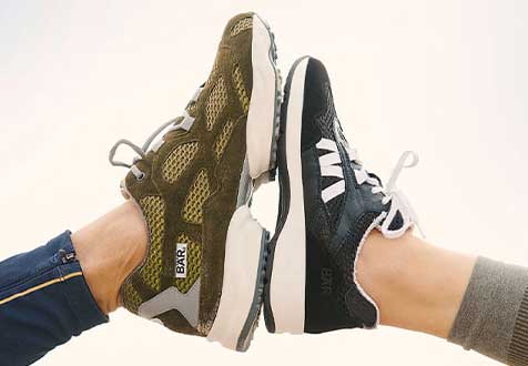 Zwei Paar Sneakers im Vergleich: Stylische Sportschuhe für Alltag und Freizeit Zwei Personen tragen unterschiedliche Sneakers, eine in olivgrün und die andere in schwarz, die zueinander zeigen.
